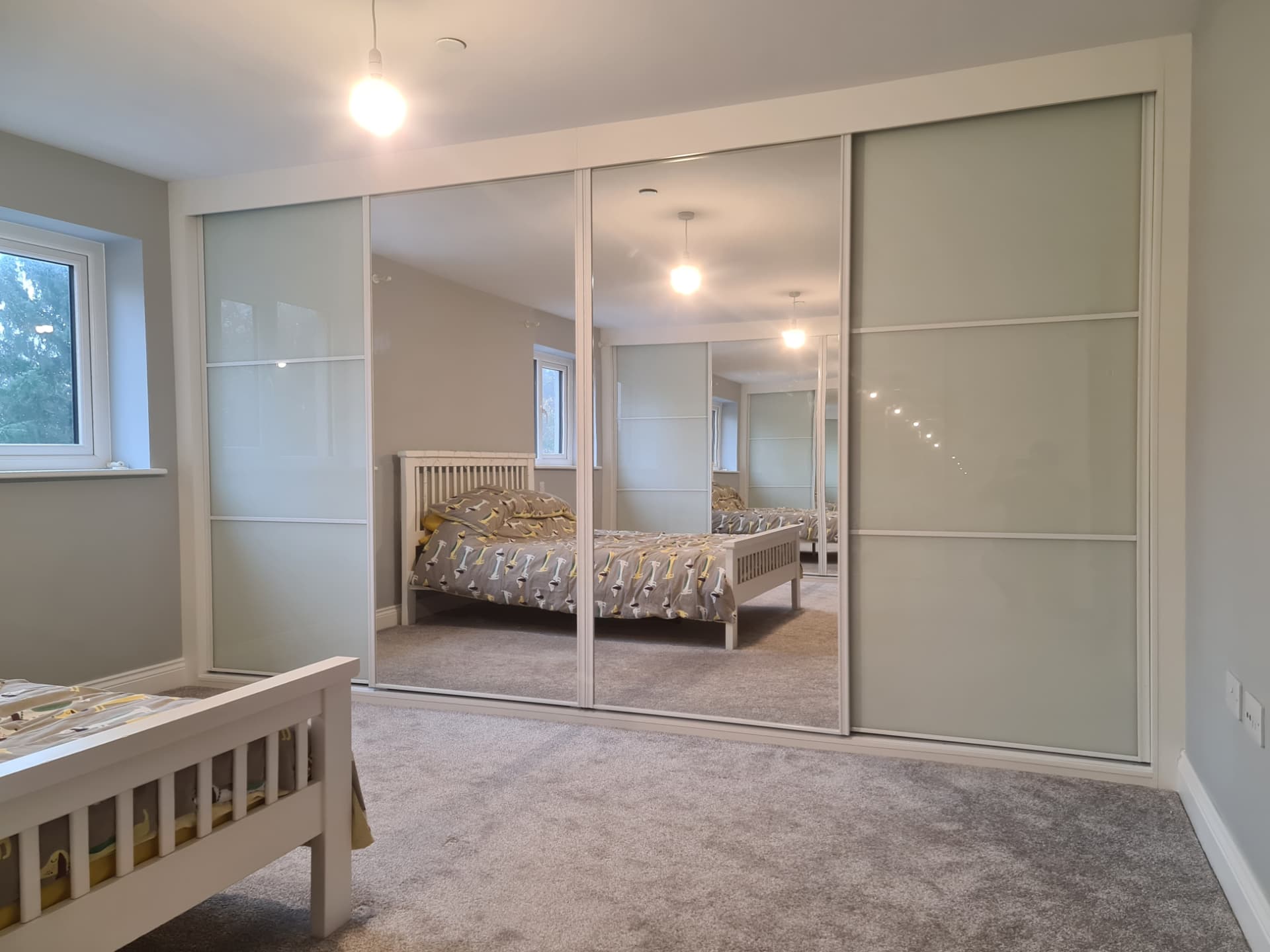 White-framed frosted glass sliding doors with a full-height central mirror panel in Litchard
