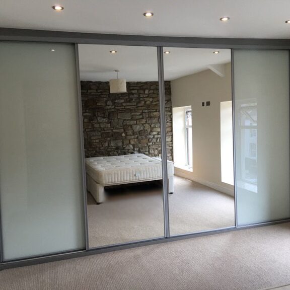 Mirror and coloured glass panels with a stone wall reflection in Taffs Well