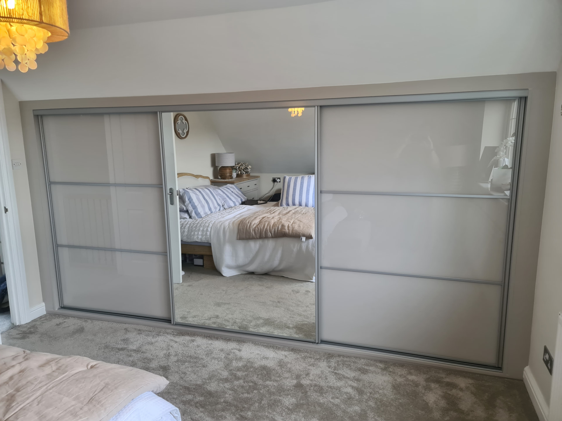 Frosted white-grey glass sliding doors with silver frames and a full central mirror door in Cardiff