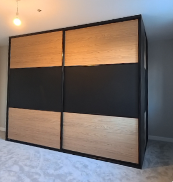 Black-framed sliding doors with oak-effect panels above and below a matte black band in Bridgend