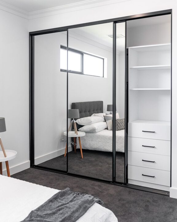 Three-door run of slim black-framed full mirror sliding doors with an open white internal section of shelves and drawers in Aberfan