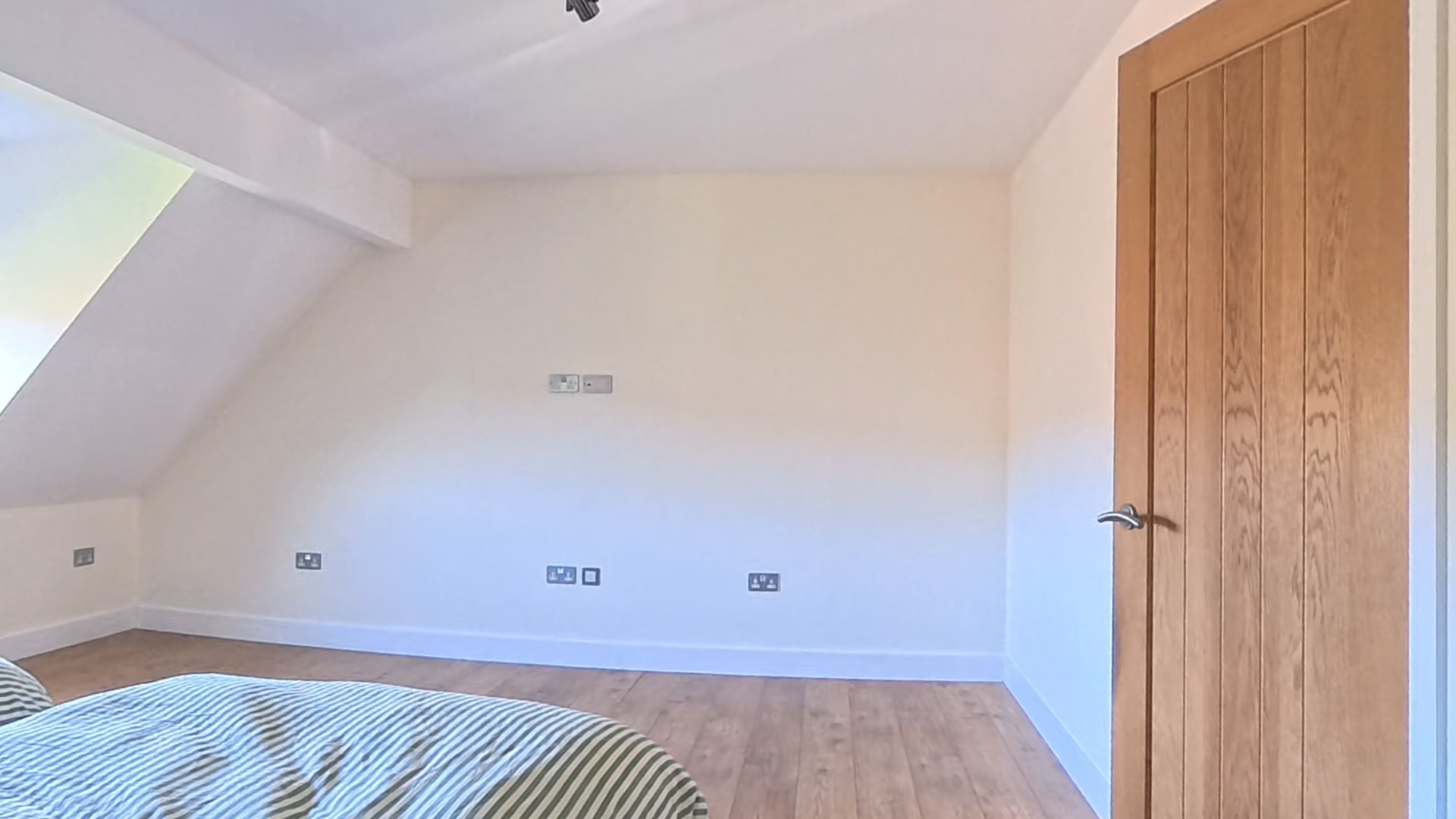 Bedroom with a sloping ceiling before fitted sliding wardrobes were installed