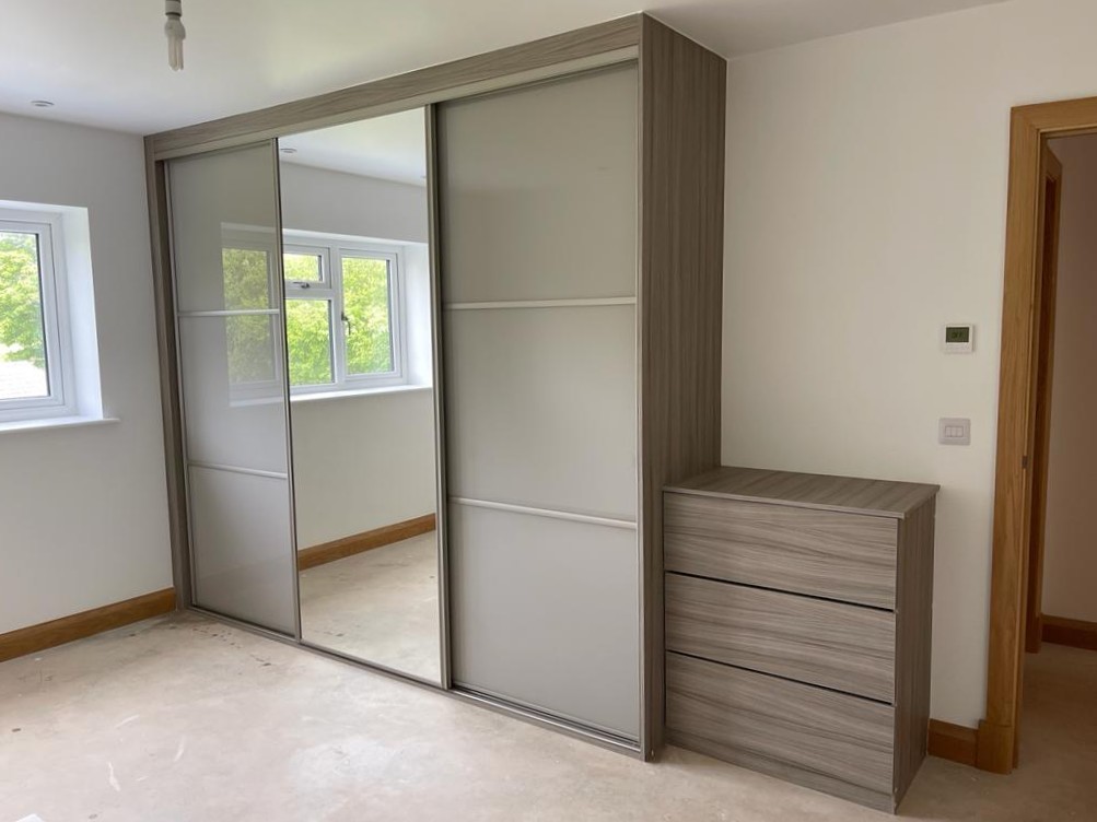 Grey wood-grain framed frosted glass sliding doors with a central mirror and matching chest of drawers in Pencoed
