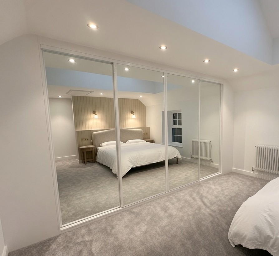 White-framed mirror doors in a long narrow bedroom in Caerphilly