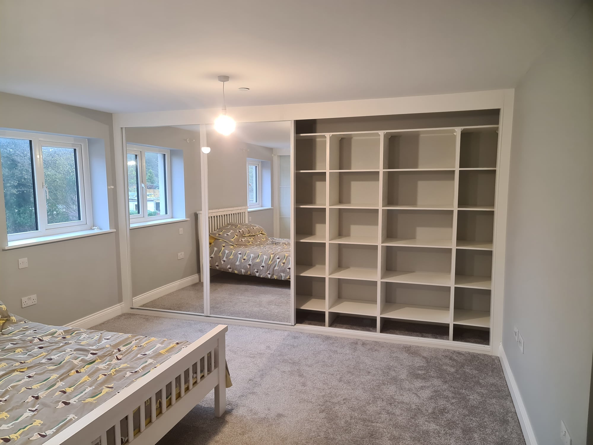 Mirror sliding doors with one open to show the white interior shelving in Port Talbot