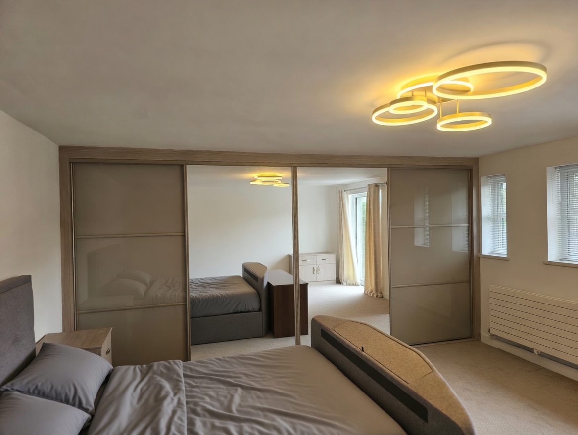 Taupe coloured glass side doors with horizontal divisions and two full-height central mirror doors in an oak-effect surround in Swansea