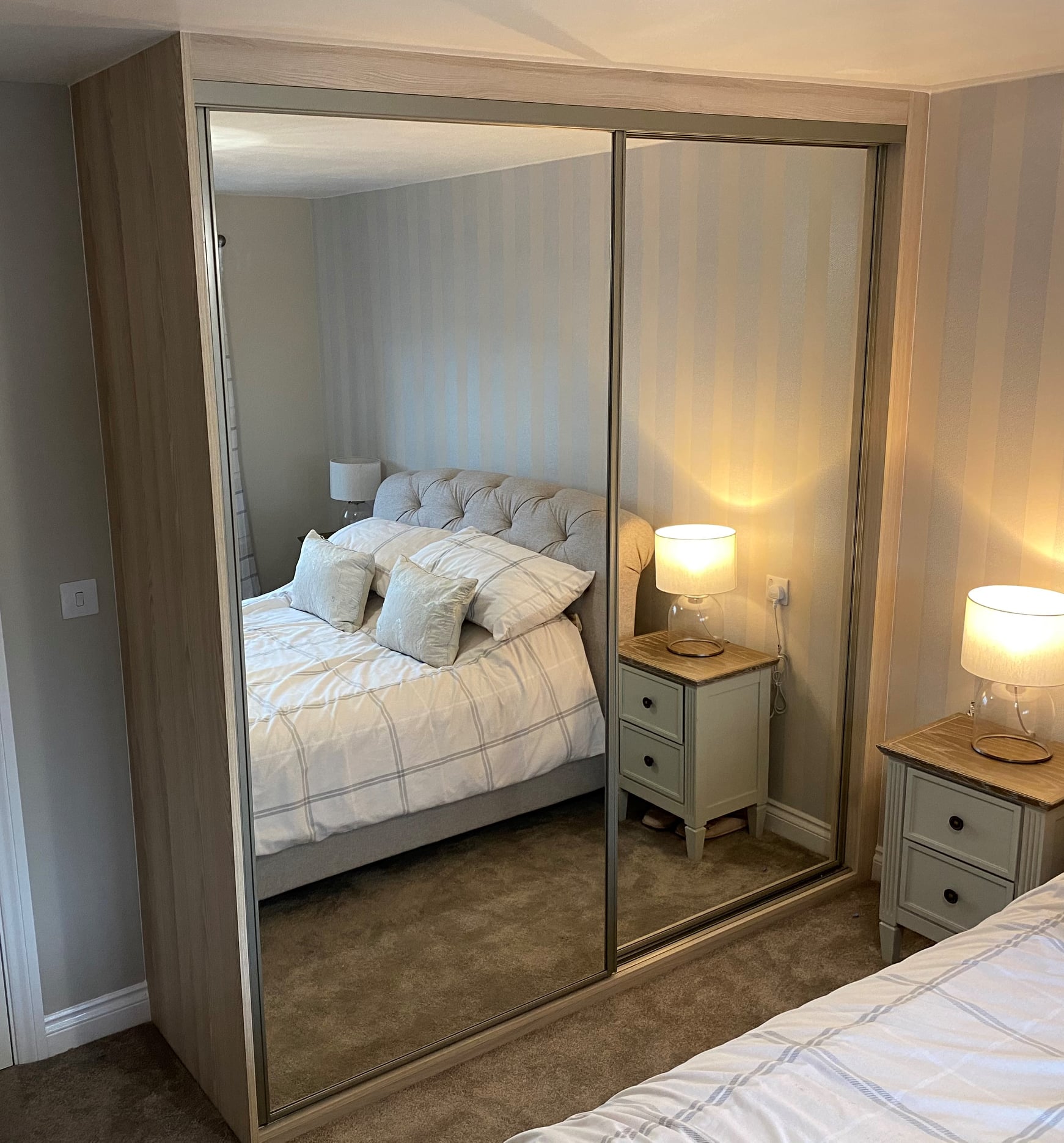 Two full-height mirror sliding doors in a light oak-effect frame in Merthyr Tydfil